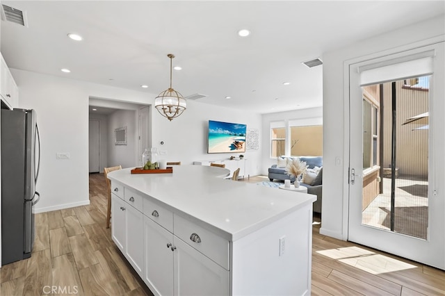 kitchen featuring light wood-style floors, freestanding refrigerator, white cabinets, and a center island