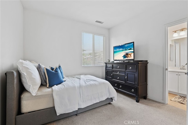 bedroom featuring light colored carpet, visible vents, and ensuite bathroom