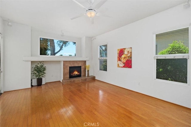 unfurnished living room featuring wood-type flooring, ceiling fan, and a fireplace