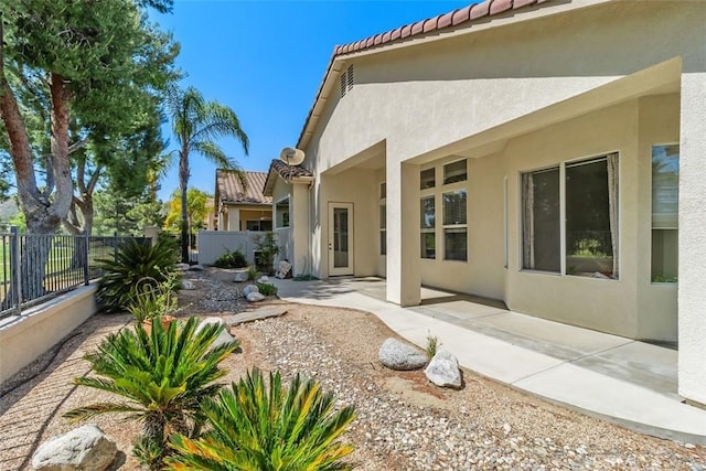 back of house with a tiled roof, fence, a patio area, and stucco siding