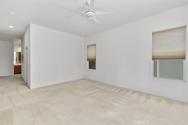 spare room featuring a ceiling fan and light carpet