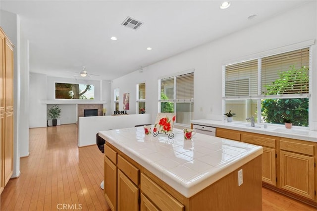 kitchen with tile countertops, visible vents, light wood finished floors, and dishwasher