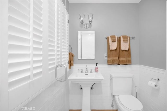 bathroom with toilet, tile walls, and wainscoting