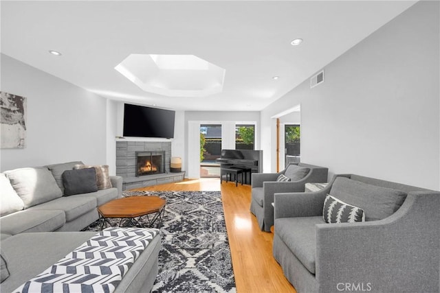 living area featuring visible vents, a fireplace, recessed lighting, light wood-type flooring, and a skylight