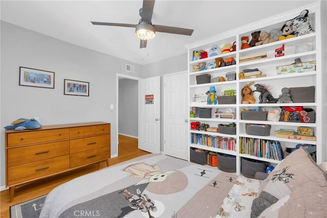 bedroom with a ceiling fan, baseboards, visible vents, and wood finished floors