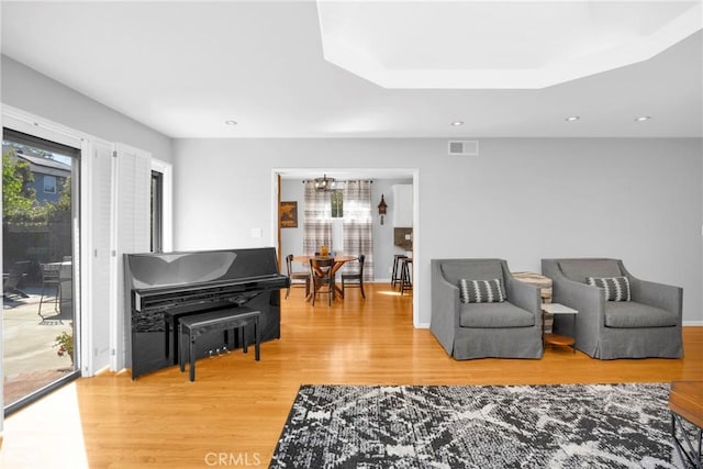 living area featuring an inviting chandelier, light wood-style floors, recessed lighting, baseboards, and visible vents