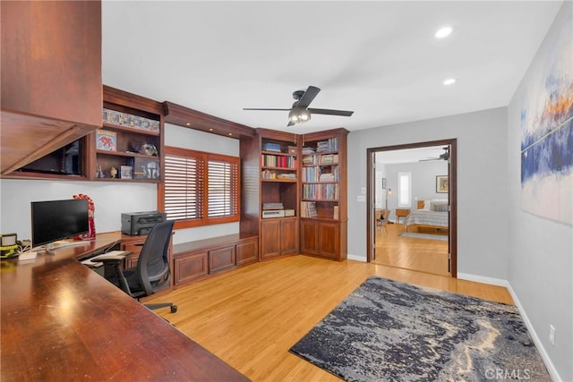 office featuring baseboards, ceiling fan, recessed lighting, built in desk, and light wood-style flooring