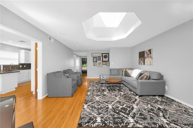 living area featuring a skylight, visible vents, a healthy amount of sunlight, and light wood-style flooring