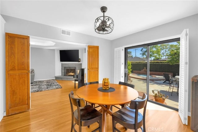 dining area featuring visible vents, light wood finished floors, and a fireplace