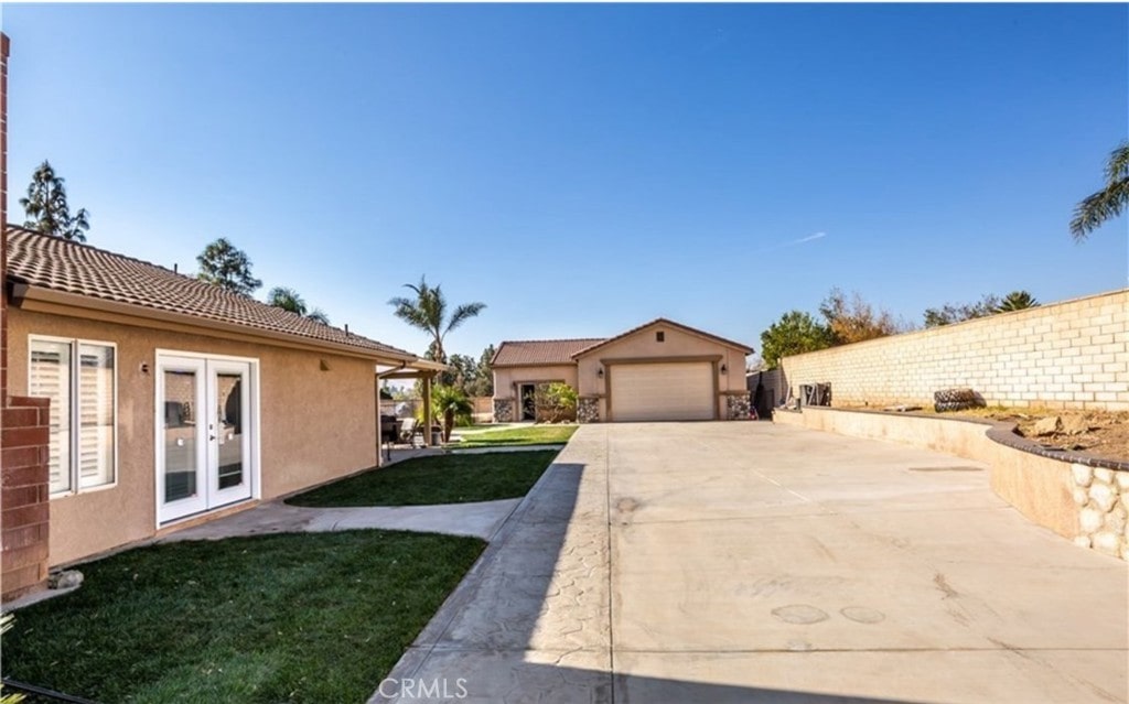 exterior space with an attached garage, driveway, french doors, and an outdoor structure