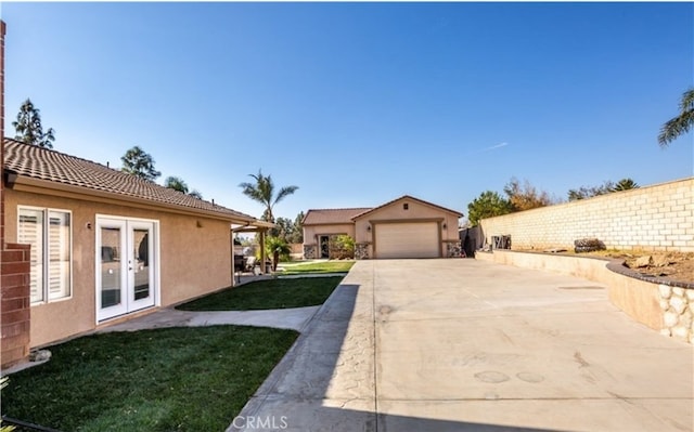 exterior space with an attached garage, driveway, french doors, and an outdoor structure