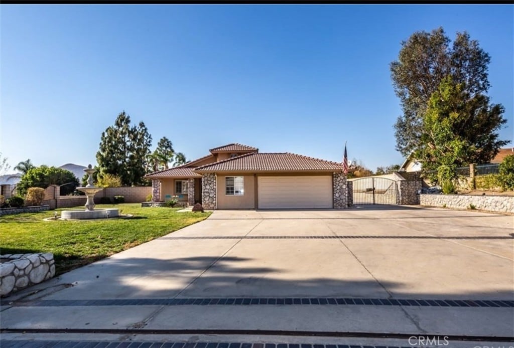 view of front of property with a tiled roof, driveway, a gate, an attached garage, and stucco siding