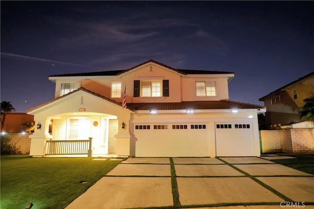 traditional home featuring a garage, stucco siding, a porch, a yard, and driveway