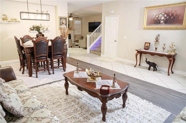 tiled living area featuring stairway, baseboards, and ceiling fan