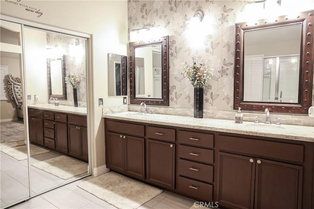 full bathroom with double vanity, tile patterned flooring, wallpapered walls, and a sink