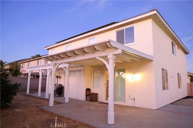 back of house featuring a pergola, fence, a patio, and stucco siding