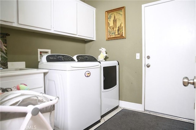 clothes washing area featuring baseboards, washer and clothes dryer, cabinet space, and light tile patterned floors