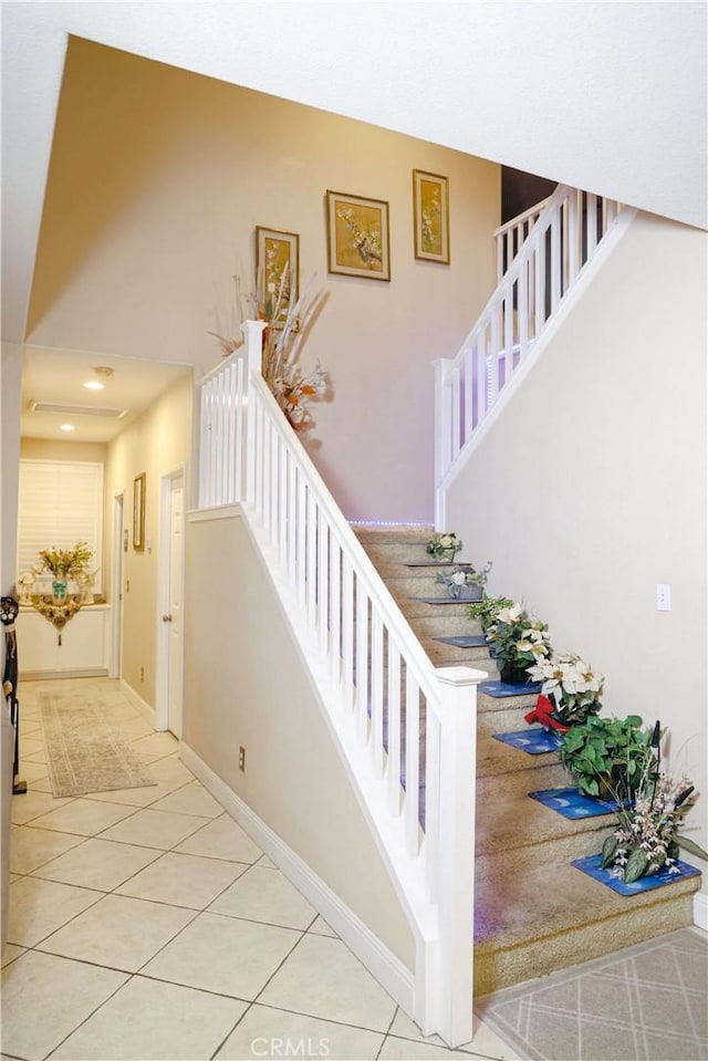 staircase featuring tile patterned floors, baseboards, and a towering ceiling