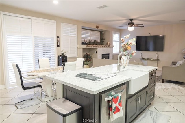 kitchen with light tile patterned flooring, open floor plan, ceiling fan, and a sink