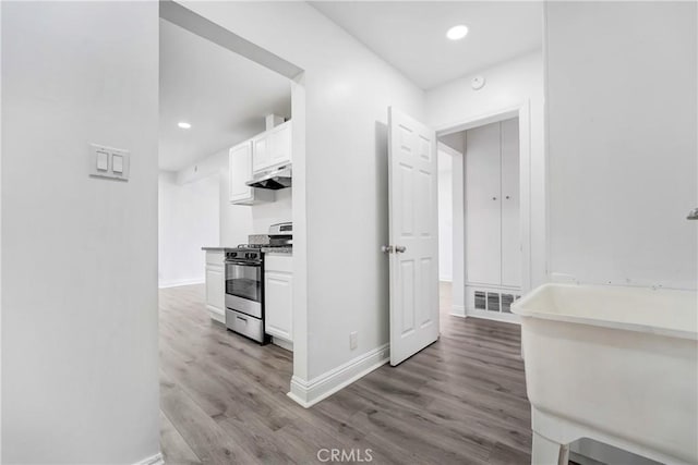 21733 Tuba St, Chatsworth, CA 91311 - interior space featuring stainless steel range with gas stovetop, baseboards, white cabinets, light wood-style floors, and under cabinet range hood