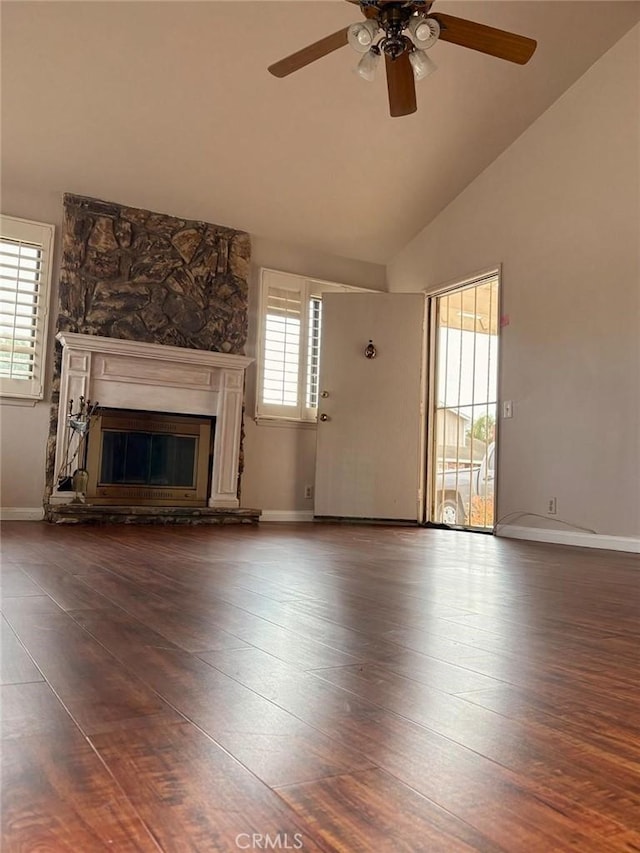 unfurnished living room with baseboards, ceiling fan, wood finished floors, and a stone fireplace