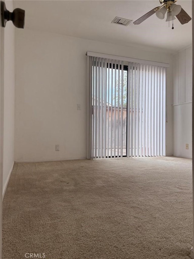 carpeted empty room with ceiling fan and visible vents