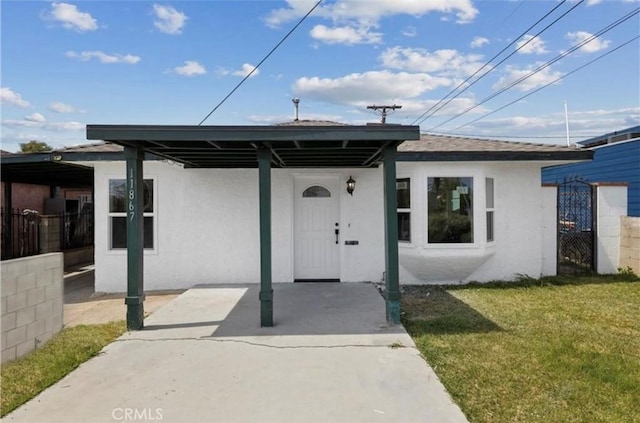11867 S San Pedro St, Los Angeles, CA 90061 - entrance to property featuring a lawn, stucco siding, fence, and a carport
