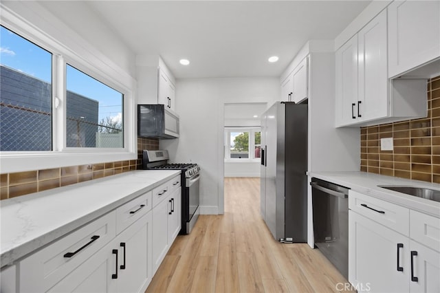11867 S San Pedro St, Los Angeles, CA 90061 - kitchen with decorative backsplash, recessed lighting, white cabinets, light wood finished floors, and stainless steel appliances