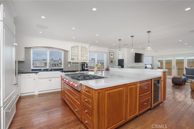 kitchen featuring a sink, stainless steel gas cooktop, open floor plan, dark wood-type flooring, and wine cooler