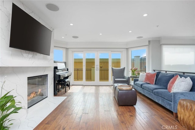 living room featuring recessed lighting, a high end fireplace, a healthy amount of sunlight, and hardwood / wood-style floors