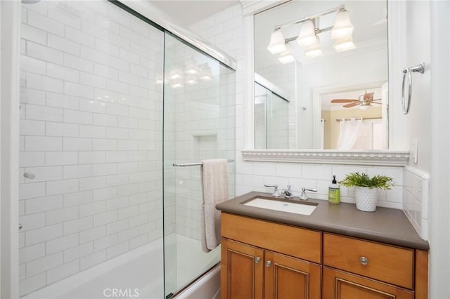 full bath featuring vanity, crown molding, shower / bath combination with glass door, tile walls, and ceiling fan