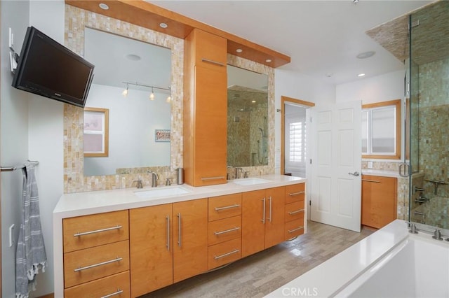 full bathroom featuring a sink, double vanity, a shower stall, and wood finished floors