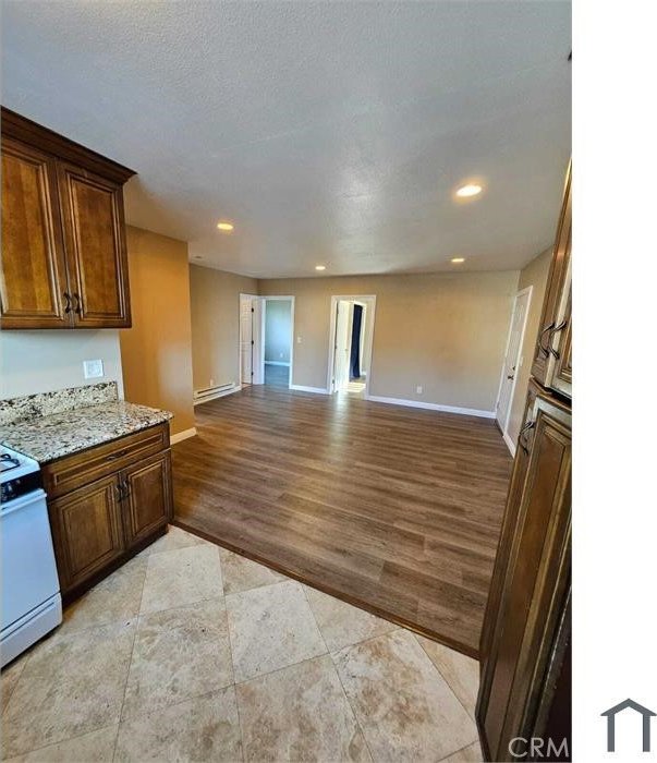 kitchen featuring white range, light wood-style flooring, recessed lighting, open floor plan, and baseboards