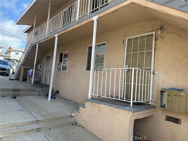 entrance to property with stucco siding and a balcony