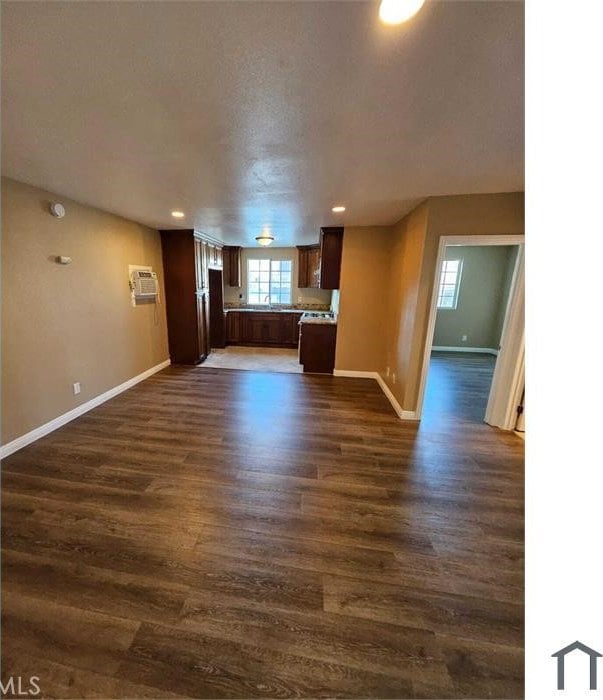 unfurnished living room featuring baseboards, recessed lighting, dark wood-type flooring, and a wall mounted AC