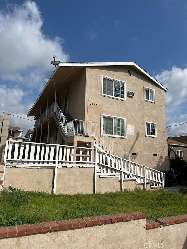 rear view of property featuring stairs and stucco siding