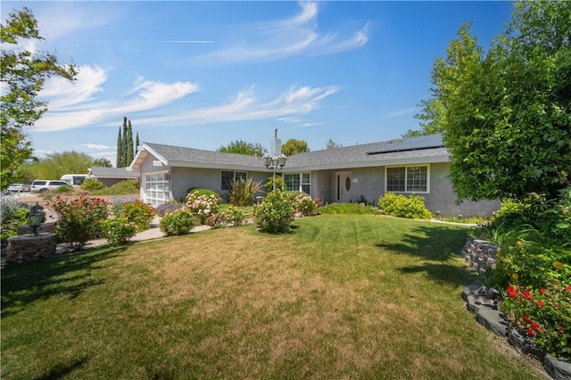 view of front of home featuring roof mounted solar panels, stucco siding, and a front yard