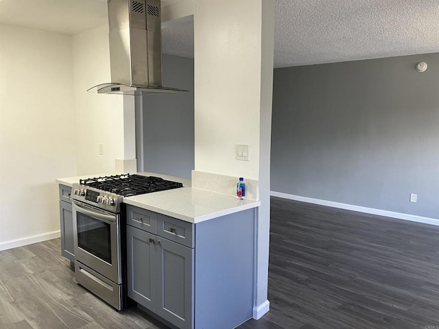 kitchen featuring wall chimney range hood, gray cabinets, gas range, baseboards, and dark wood-style floors