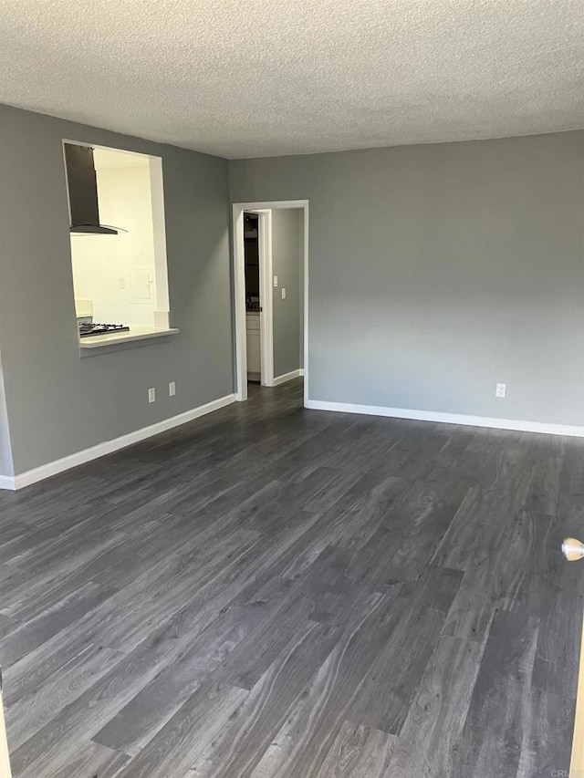 spare room with baseboards, a textured ceiling, and dark wood-type flooring