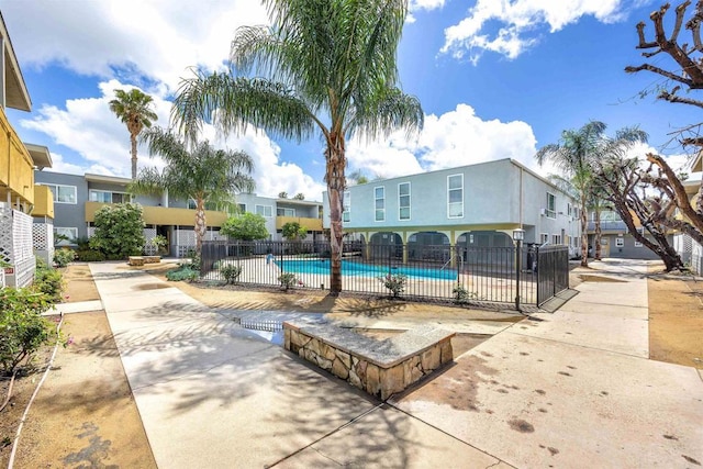 community pool featuring fence, a residential view, and a patio area