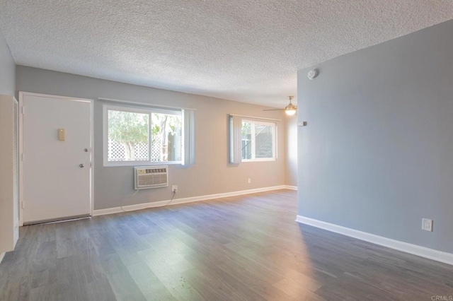 interior space with a textured ceiling, a wall mounted AC, a healthy amount of sunlight, and wood finished floors