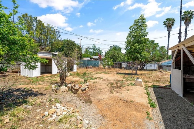 view of yard with fence, an outdoor structure, and a storage unit