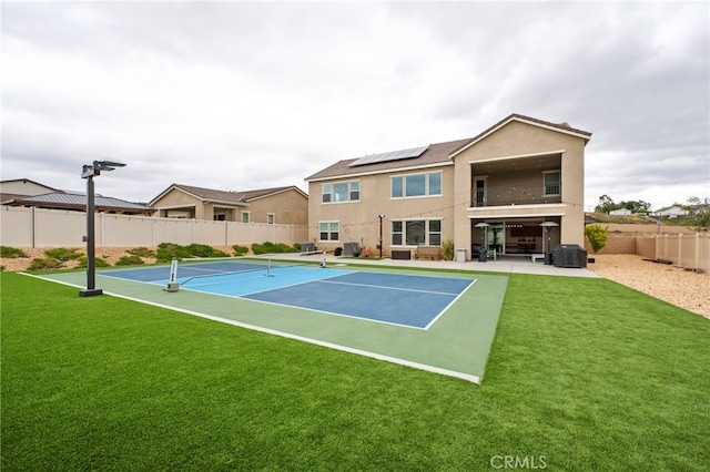 view of tennis court featuring fence and a yard