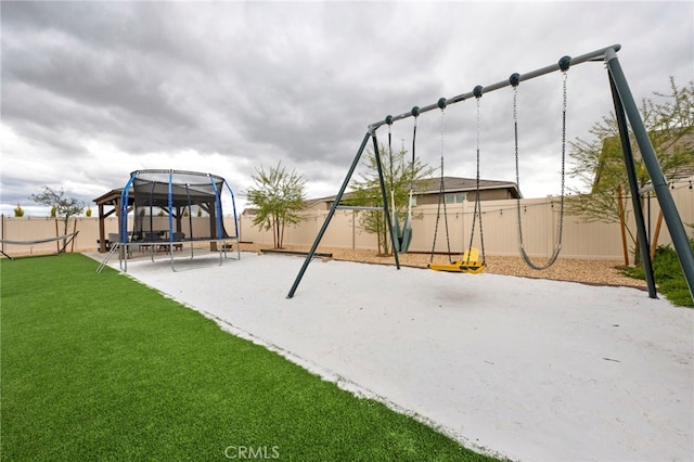 view of jungle gym featuring a lawn, a trampoline, and a fenced backyard