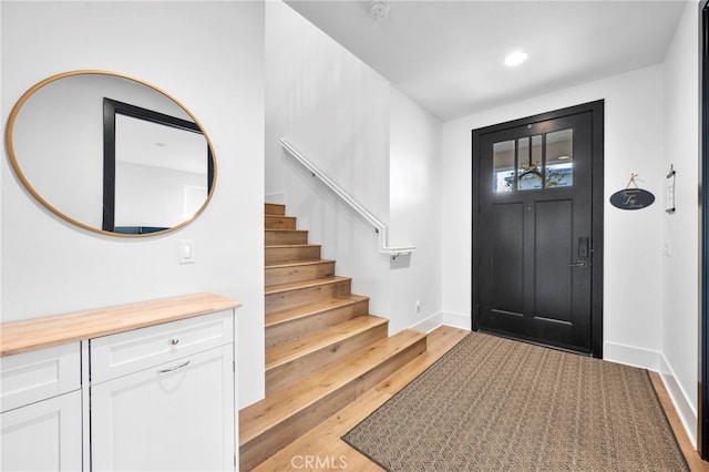 foyer entrance with stairway, baseboards, recessed lighting, and light wood finished floors