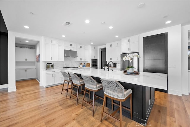kitchen featuring white cabinets, appliances with stainless steel finishes, recessed lighting, under cabinet range hood, and visible vents