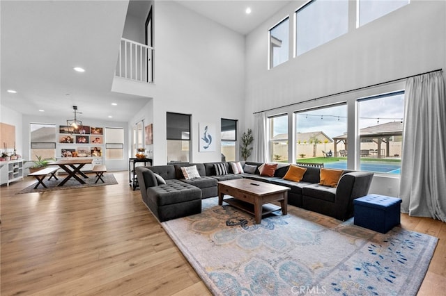 living room with recessed lighting, a high ceiling, a wealth of natural light, and light wood-style flooring