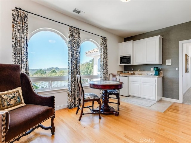 dining room featuring light wood-type flooring, baseboards, and visible vents