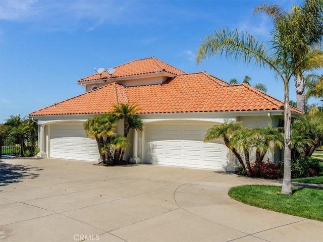mediterranean / spanish house featuring a tiled roof, an attached garage, driveway, and stucco siding