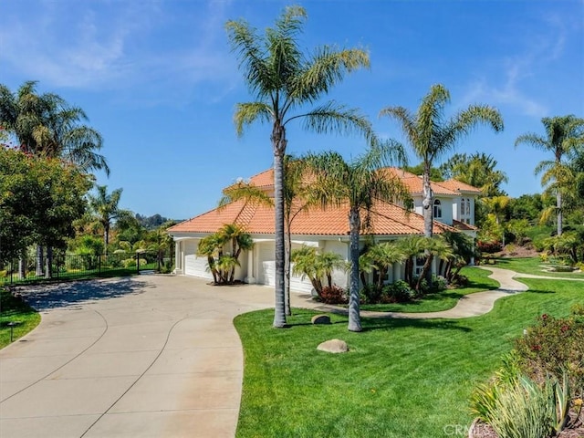 mediterranean / spanish home featuring a tiled roof, driveway, a front yard, a garage, and stucco siding